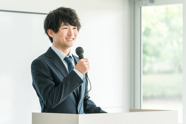 ステージ上でプレゼンをする男性