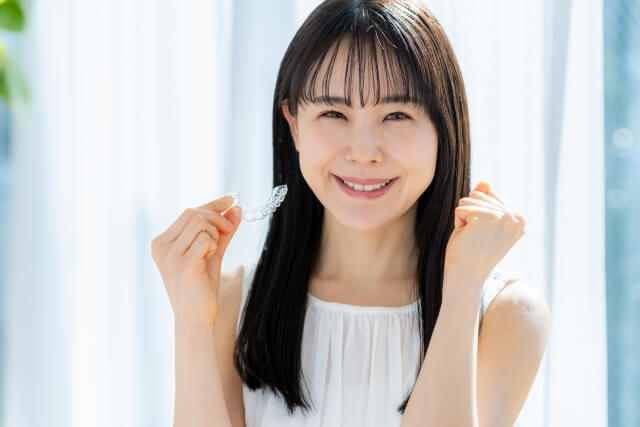 マウスピースを持って笑う女性