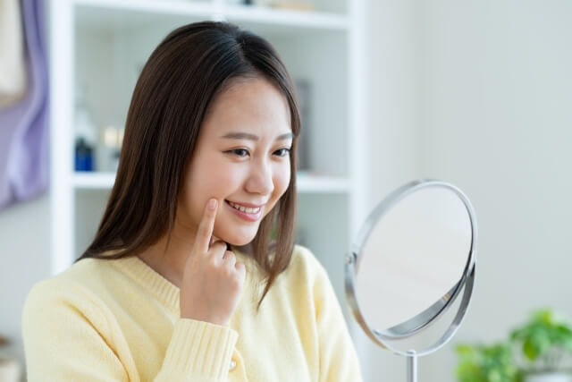 鏡で口元や歯を見る女性