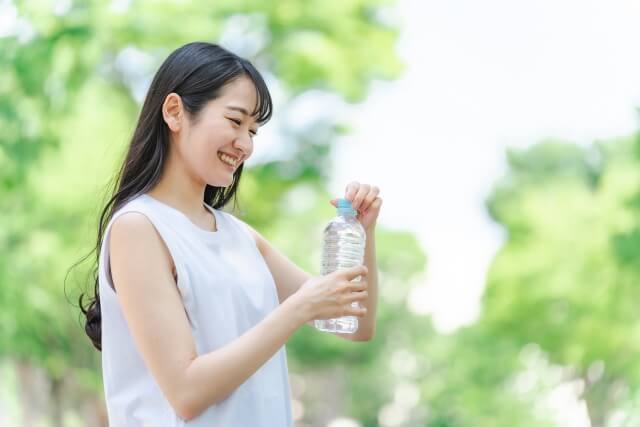 ペットボトルの水を飲む女性