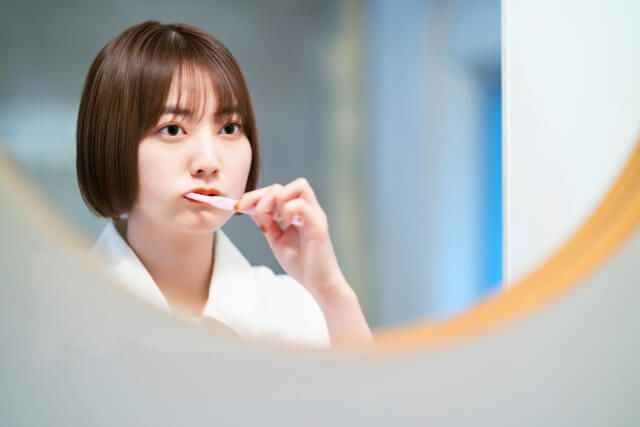 鏡の前で歯磨きをする若い女性
