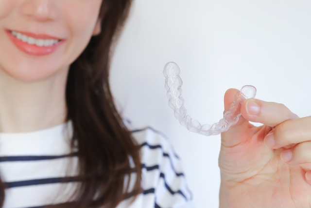 マウスピースを手に持って微笑む女性の口元