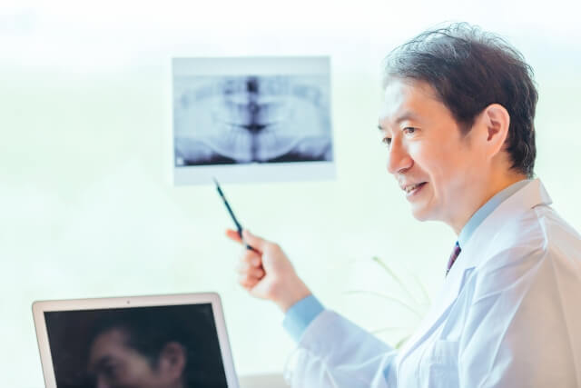 レントゲンを見せながら患者に説明をする歯科医師